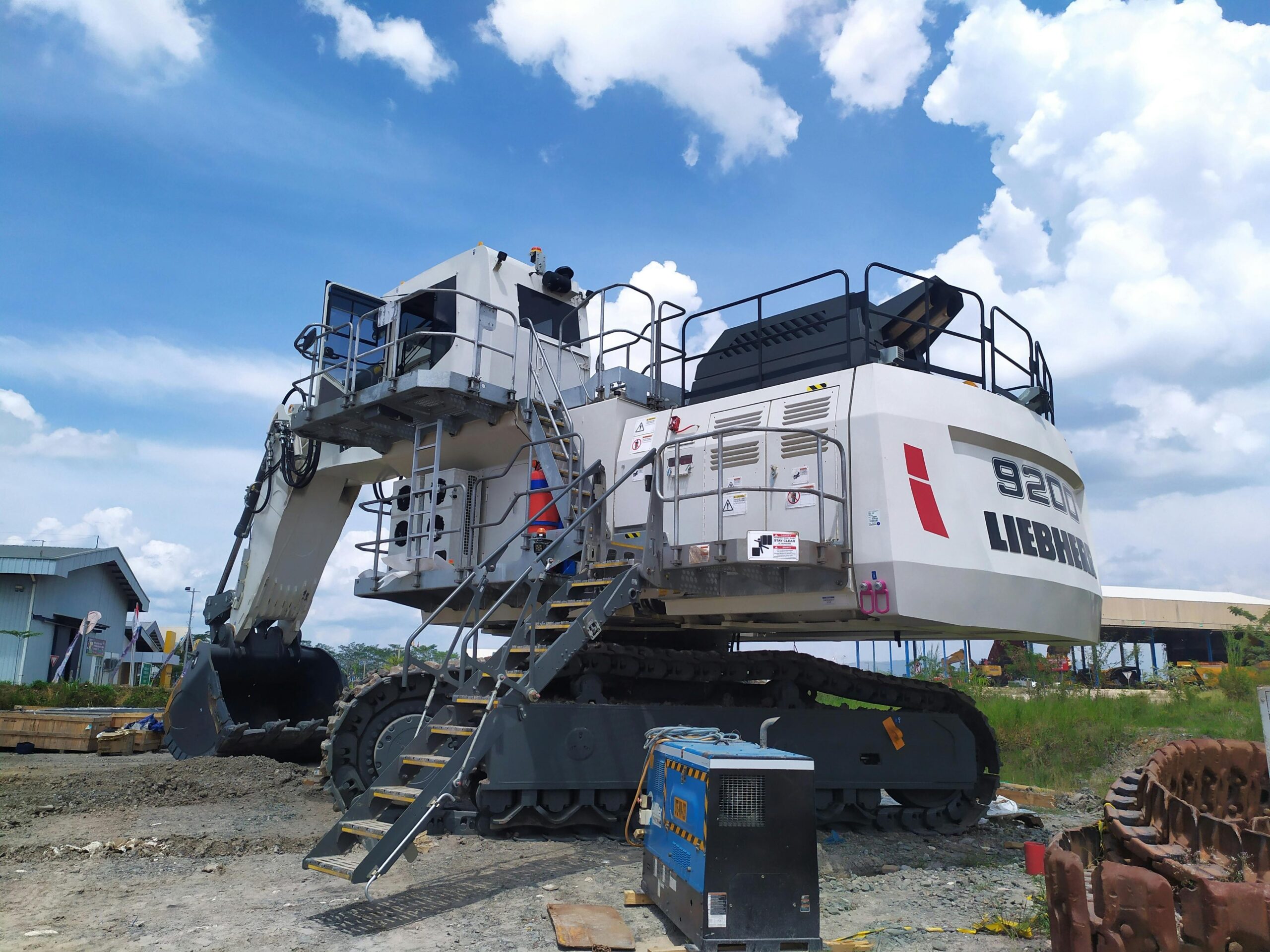 Large Liebherr excavator at an Indonesian construction site under a bright blue sky.